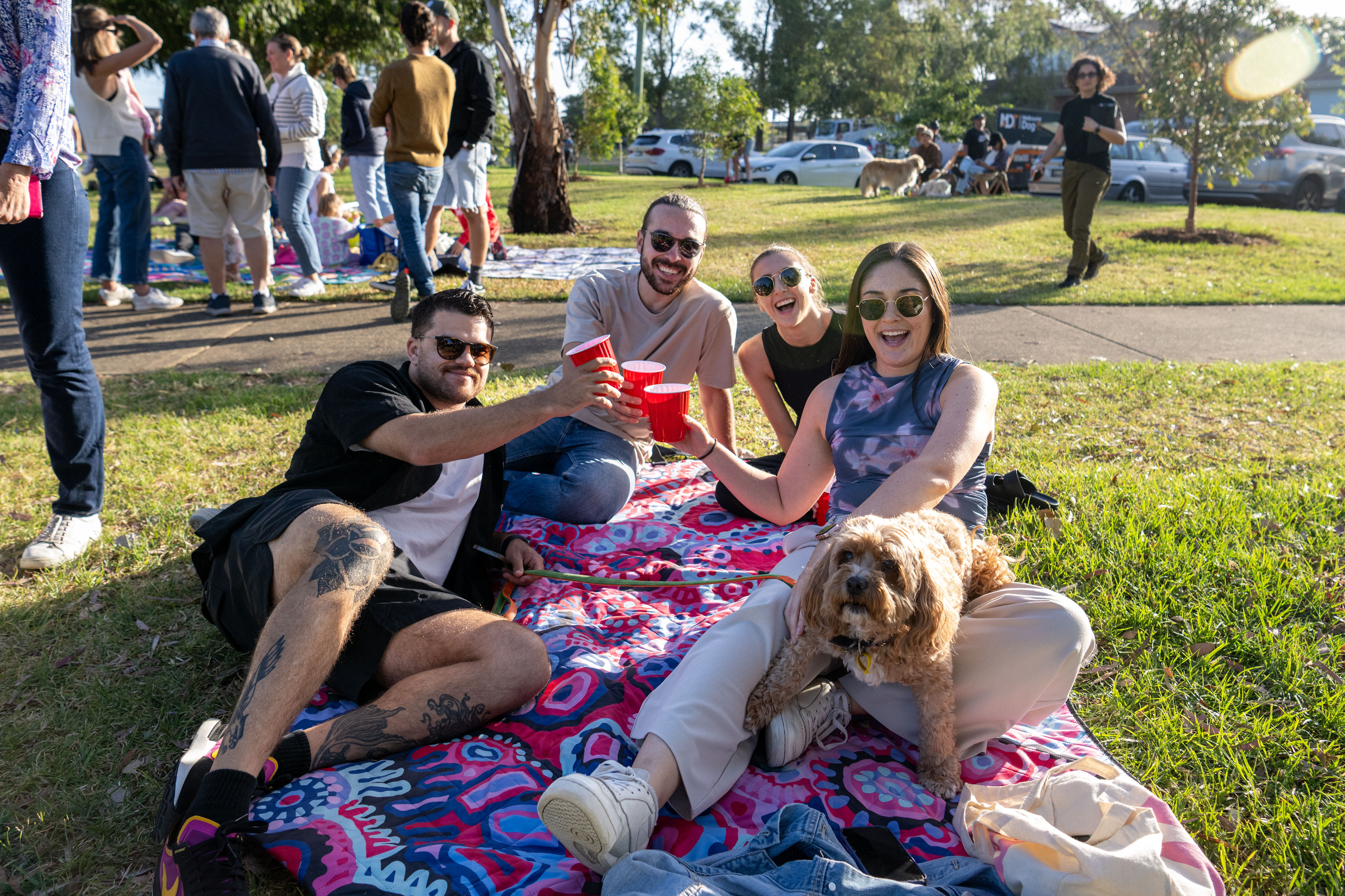 Group of people smiling on picnic rug with dog