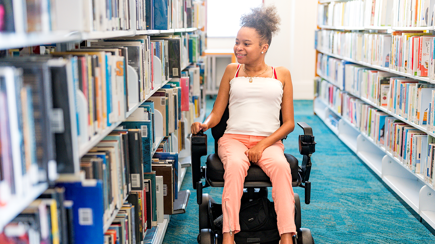 Girl in an electric wheelchair in a library