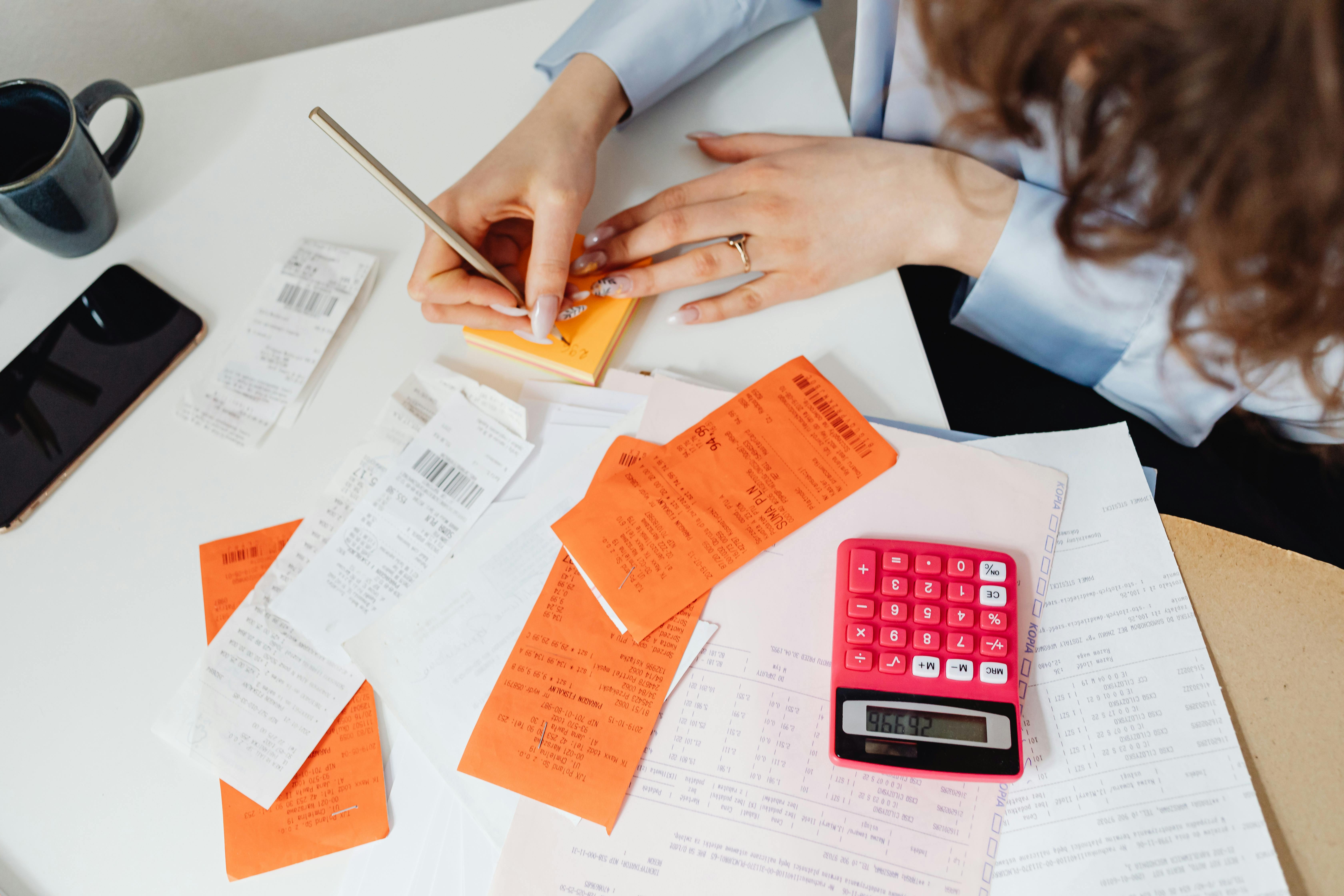 Person writing on notepad, calculator on the side