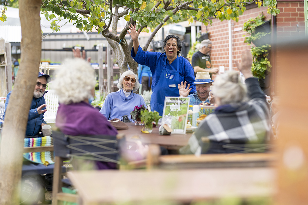 People in a community garden café waving